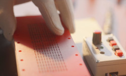 Hand in a white glove adjusting a layer with a grid of small holes.